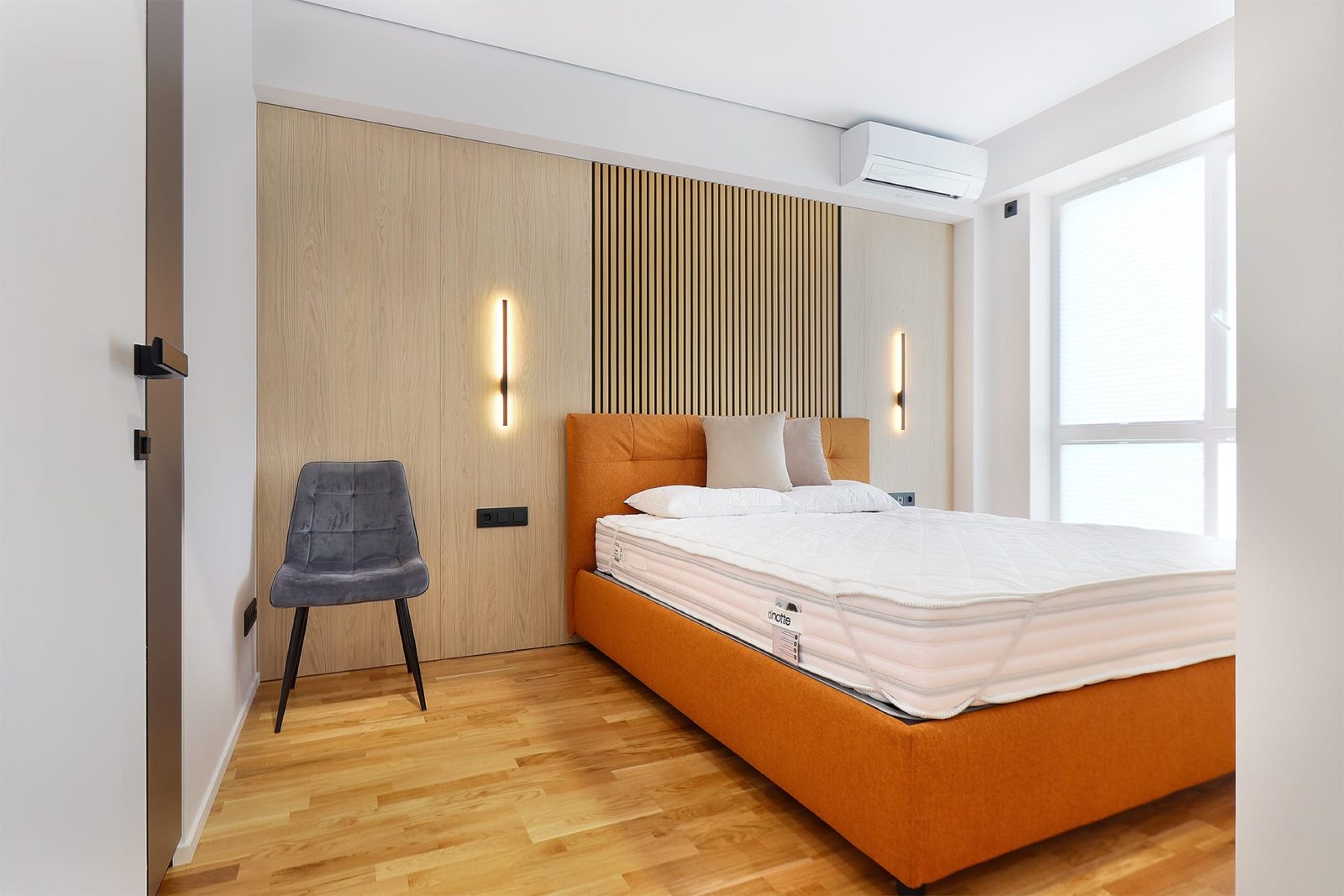 Orange bed with wall lights and armchair
